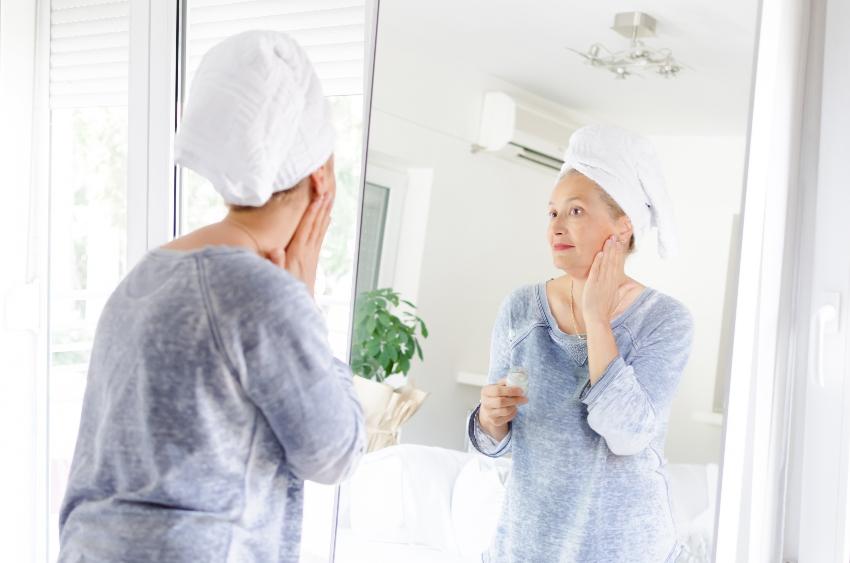 Frau mit Couperose cremt sich ein