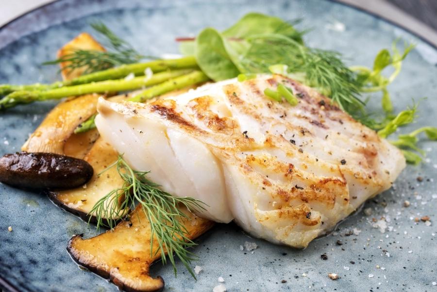 Gebratenes Kabeljau Fisch Filet mit gruenem Spargel und Pilzen