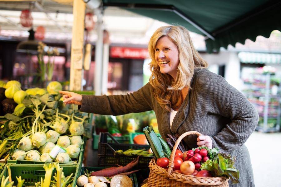 Frau kauft Obst und Gemuese auf dem Markt